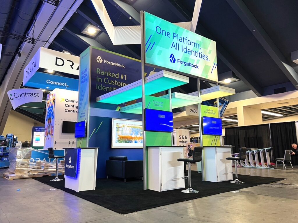 20 ft. Trade Show Island Display With Backlit Graphics, Open Floor Space Exhibit Design, Flat Screen Workstations and Lounge Area